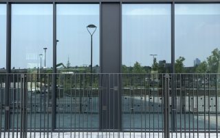 Pavimentazione in autobloccanti Paver Londra a Cascina Merlata, con recinzione metallica e facciata vetrata riflettente.