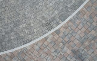 Pavimentazione esterna realizzata con autobloccanti di diverse tonalità di grigio e rosa.
