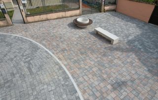 Pavimentazione esterna realizzata con autobloccanti di diverse tonalità di grigio e rosa.