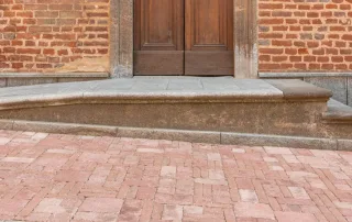 Pavimentazione in mattoni anticati disposti in un motivo geometrico, con tonalità calde e sfumature naturali.