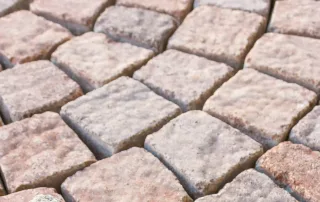 Pavimentazione in mattoni quadrati con tonalità di beige e rosa.