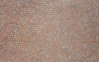 Pavimentazione in mattoni disposti in forme circolari, con tonalità calde di rosa e beige.