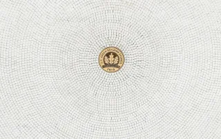 Pavimentazione in mosaico chiaro con disposizione radiale, caratterizzata da un medaglione centrale decorativo con iscrizione "Green Building Council 2018".
