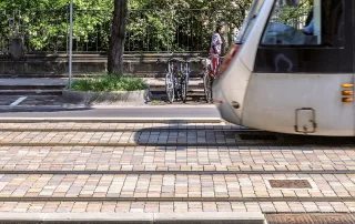 Pavimentazione in pietra con binari integrati, su cui transita un tram.