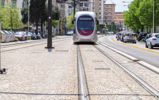 Pavimentazione in pietra con binari integrati, su cui transita un tram.