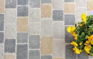 Pavimentazione in pietra anticata con blocchi di colore grigio e inserti beige.