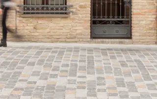 Pavimentazione in pietra anticata con blocchi di colore grigio e inserti beige.