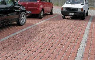Parcheggio con pavimentazione drenante in cemento e fughe riempite di ghiaia.