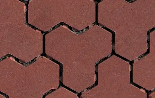 Pavimentazione drenante in cemento con blocchi ad incastro color rosso e fughe riempite di ghiaia.