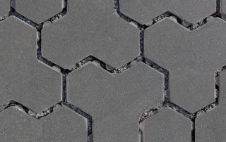 Pavimentazione drenante in cemento con blocchi ad incastro color grigio e fughe riempite di ghiaia.
