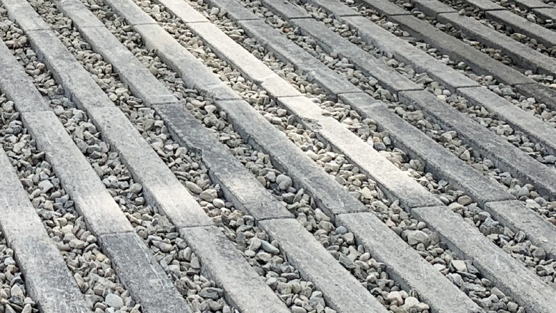 avimentazione grigliata in cemento di colore grigio, composta da elementi rettangolari disposti parallelamente con spazi riempiti da ghiaia.
