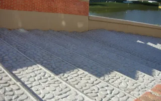Rampa in cemento con pavimentazione a effetto ciottolato e canalette drenanti.