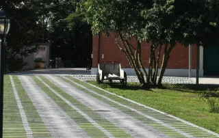 Pavimentazione drenante in cemento con fughe erbose e design a listoni.