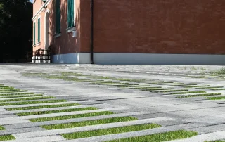 Pavimentazione drenante in cemento con fughe erbose e design a listoni.
