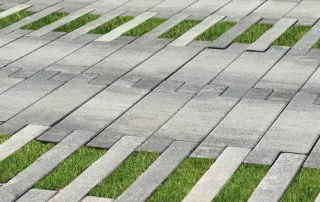 Pavimentazione drenante in cemento con fughe erbose e design a listoni.