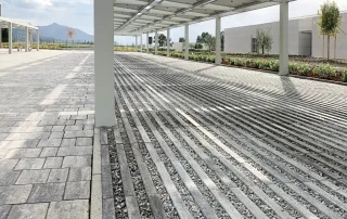 avimentazione grigliata in cemento di colore grigio, composta da elementi rettangolari disposti parallelamente con spazi riempiti da ghiaia.