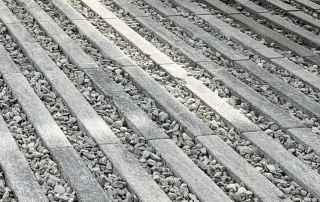 avimentazione grigliata in cemento di colore grigio, composta da elementi rettangolari disposti parallelamente con spazi riempiti da ghiaia.