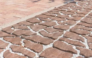 Pavimentazione drenante in pietra con fughe riempite di ghiaia bianca.