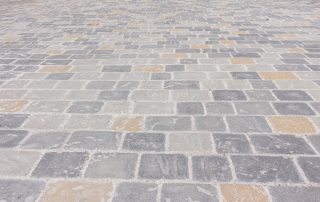pavimentazione in pietra con blocchi rettangolari grigi e ocra.