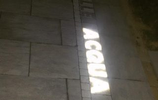Pavimentazione esterna realizzata con masselli autobloccanti Paver a Terme di Comunanza, con inserto decorativo che riporta la scritta 'Acqua'.