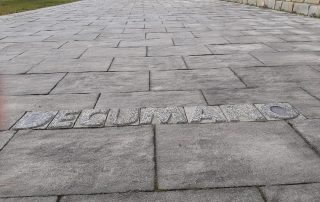 Pavimentazione esterna realizzata con masselli autobloccanti Paver a Terme di Comunanza con inserto decorativo che riporta la scritta 'Decumano'.