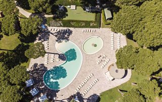 Pavimentazione in masselli autobloccanti attorno a due piscine, una più ampia e una più piccola con area giochi d'acqua.