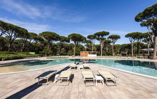 Pavimentazione in masselli autobloccanti attorno a due piscine, una più ampia e una più piccola con area giochi d'acqua.