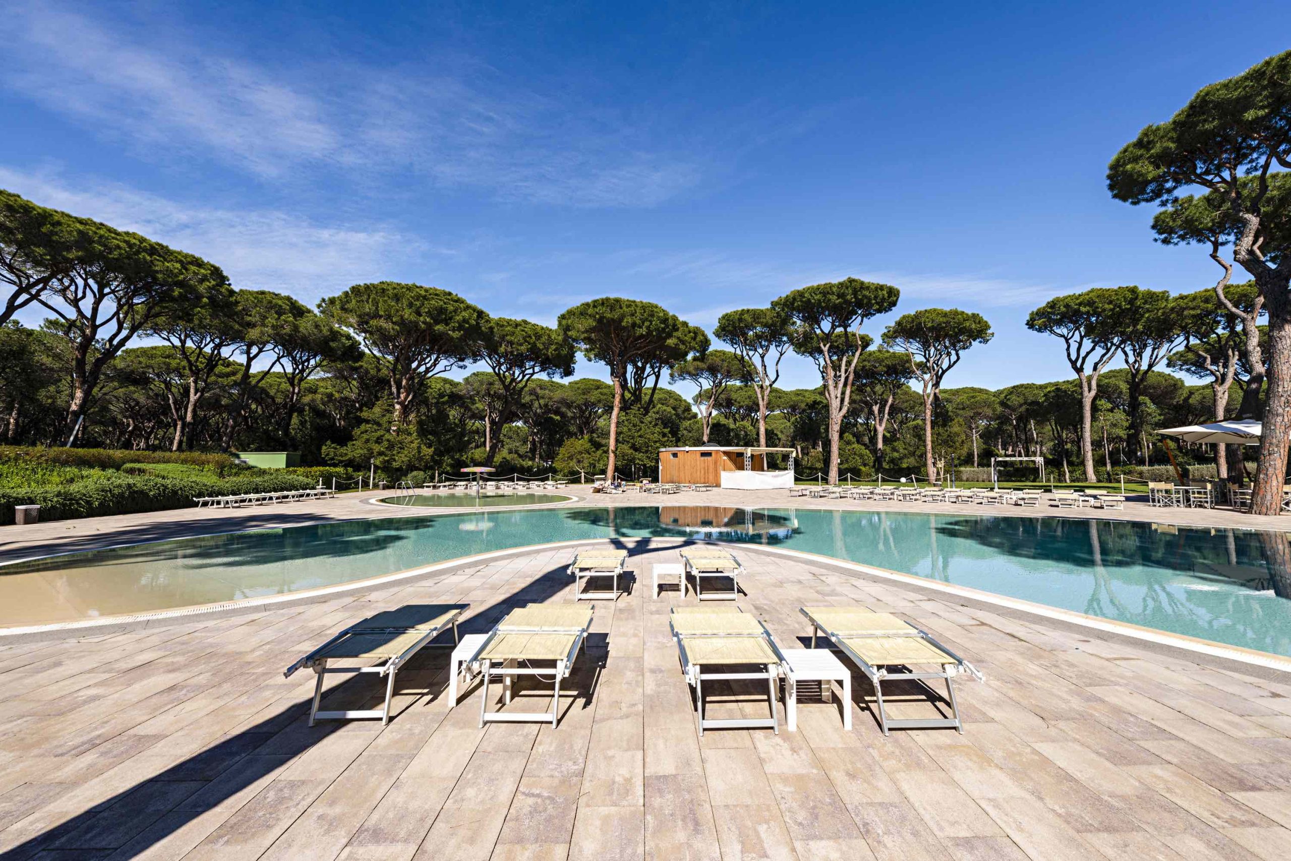 Pavimentazione in masselli autobloccanti attorno a due piscine, una più ampia e una più piccola con area giochi d'acqua.