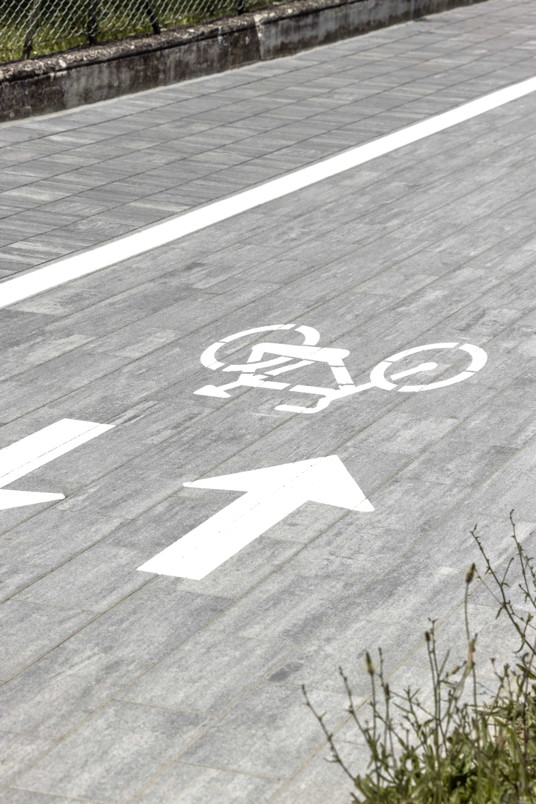Pista ciclabile in masselli autobloccanti grigi.