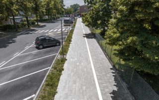 Pista ciclabile in masselli autobloccanti grigi.