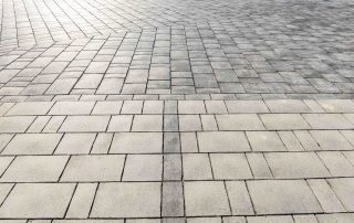 Pavimentazione in blocchi rettangolari con diverse tonalità di grigio.