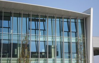 Facciata in vetro di un edificio moderno con struttura metallica verticale.