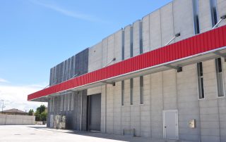 Edificio industriale con pannelli prefabbricati in cemento una lunga pensilina rossa.