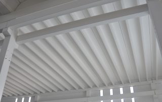 Soffitto di un capannone industriale con travi bianche.