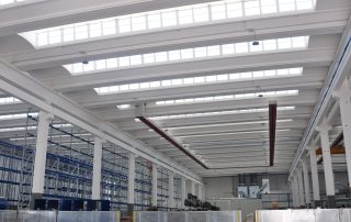 Soffitto di un capannone industriale con travi bianche.