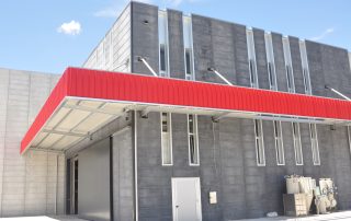 Edificio industriale con pannelli prefabbricati in cemento una lunga pensilina rossa.