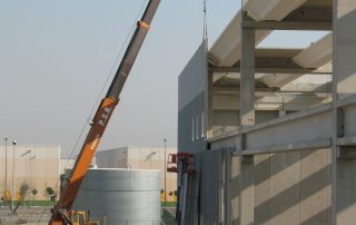Assemblaggio di una struttura prefabbricata in cemento con travi metalliche.