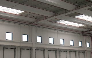 Interno di un magazzino logistico con ampie baie di carico, soffitto con lucernari.
