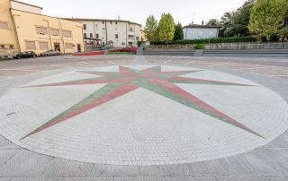 Pavimentazione con una grande rosa dei venti in mattonelle bianche, rosse e verdi.