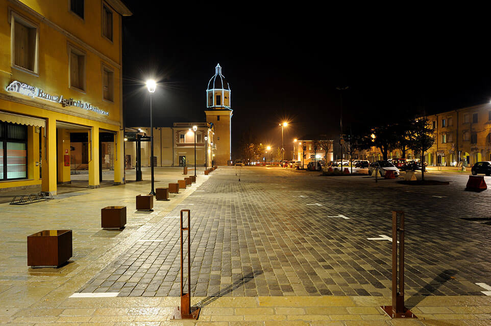 Piazza urbana illuminata di notte con pavimentazione in pietra.