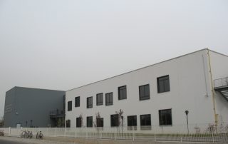 Edificio prefabbricato con pareti esterne lisce in calcestruzzo bianco e serramenti in alluminio scuro.