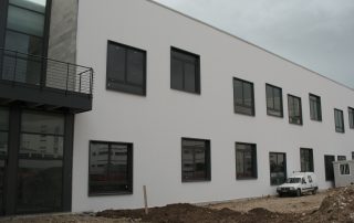 Edificio prefabbricato con pareti esterne lisce in calcestruzzo bianco e serramenti in alluminio scuro