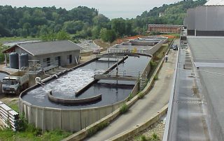 Una grande vasca industriale di forma rettangolare. La vasca contiene un liquido scuro e denso.