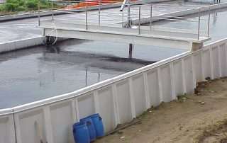 Una grande vasca industriale di forma rettangolare. La vasca contiene un liquido scuro e denso.