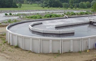 Una grande vasca industriale di forma rettangolare. La vasca contiene un liquido scuro e denso.