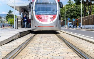 Pavimentazione in pietra con binari integrati, su cui transita un tram.