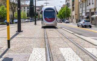 Pavimentazione in pietra con binari integrati, su cui transita un tram.
