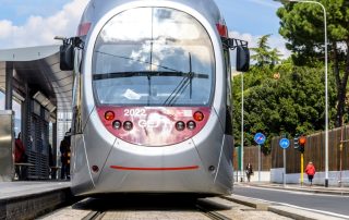 Pavimentazione in pietra con binari integrati, su cui transita un tram.