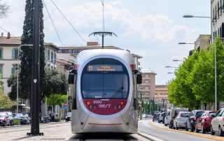 Pavimentazione in pietra con binari integrati, su cui transita un tram.