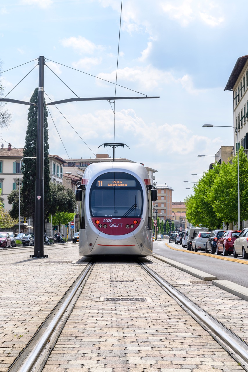 Pavimentazione in pietra con binari integrati, su cui transita un tram.